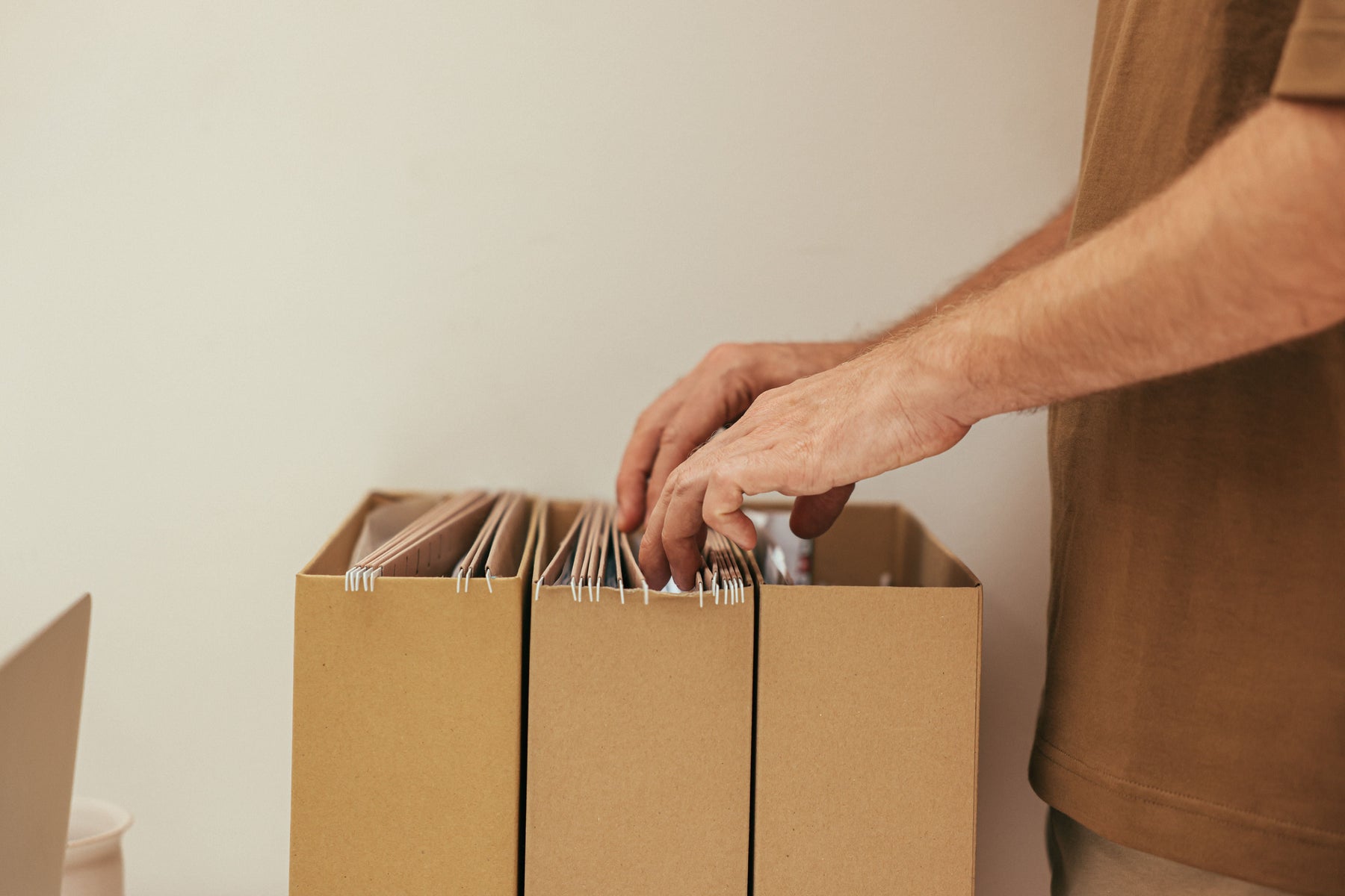 Man organizing hanging file folders in cardboard storage boxes
